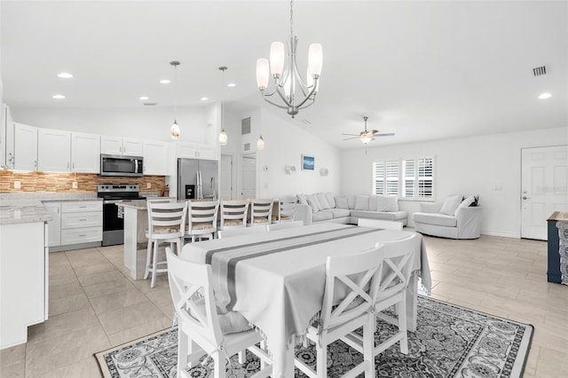 tiled dining space with ceiling fan with notable chandelier and vaulted ceiling