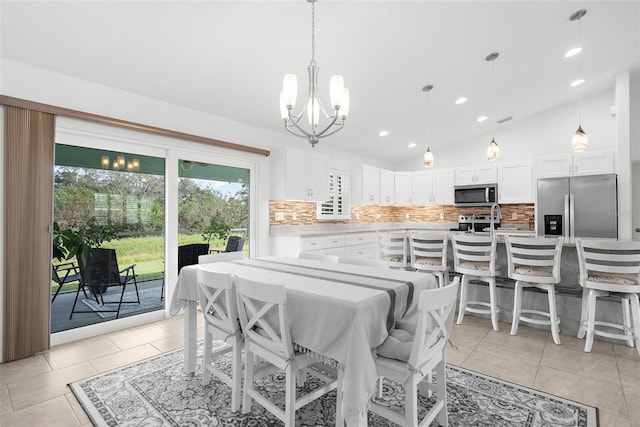 dining area with light tile patterned floors, vaulted ceiling, and a notable chandelier