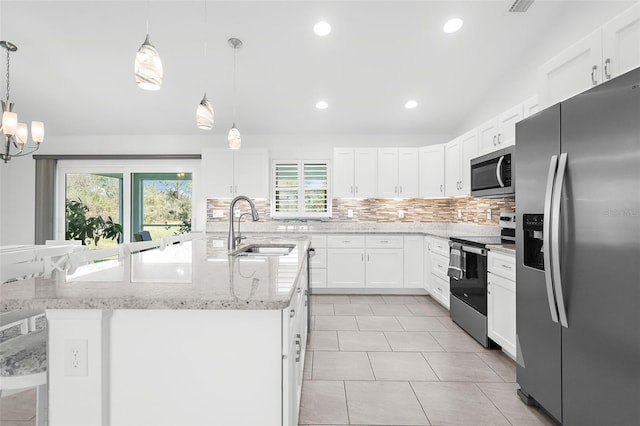 kitchen with stainless steel appliances, sink, hanging light fixtures, a kitchen island with sink, and white cabinets