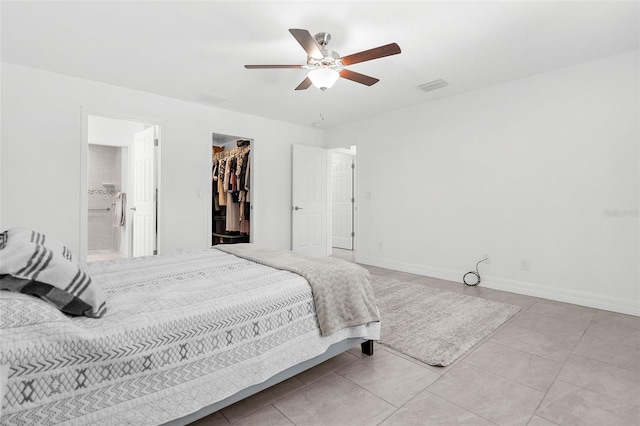 tiled bedroom featuring connected bathroom, a closet, a spacious closet, and ceiling fan