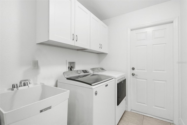 washroom with cabinets, light tile patterned floors, sink, and washer and clothes dryer