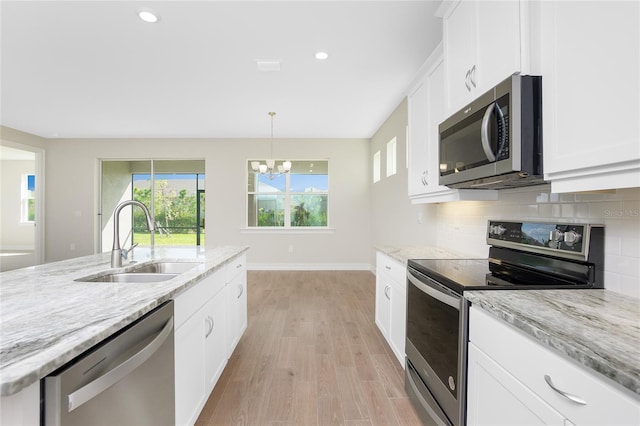 kitchen with white cabinets, appliances with stainless steel finishes, sink, and light hardwood / wood-style flooring