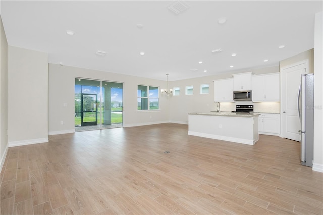 unfurnished living room with sink, light wood-type flooring, and an inviting chandelier