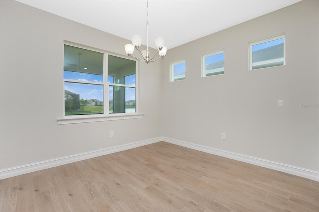 empty room featuring light hardwood / wood-style flooring and a notable chandelier