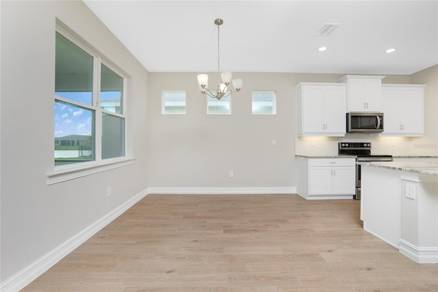 kitchen with white cabinetry, appliances with stainless steel finishes, light stone countertops, and a healthy amount of sunlight