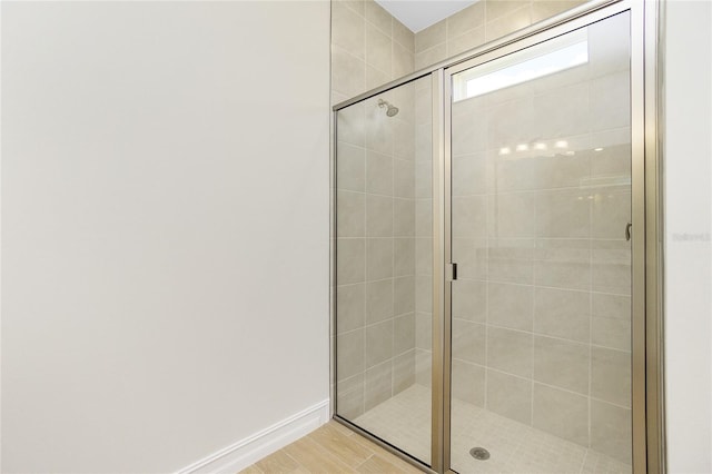 bathroom with hardwood / wood-style flooring and a shower with shower door