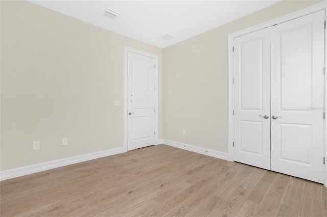 unfurnished bedroom with light hardwood / wood-style floors and a closet