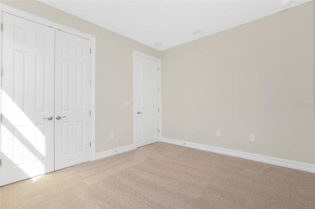 unfurnished bedroom featuring light carpet and a closet