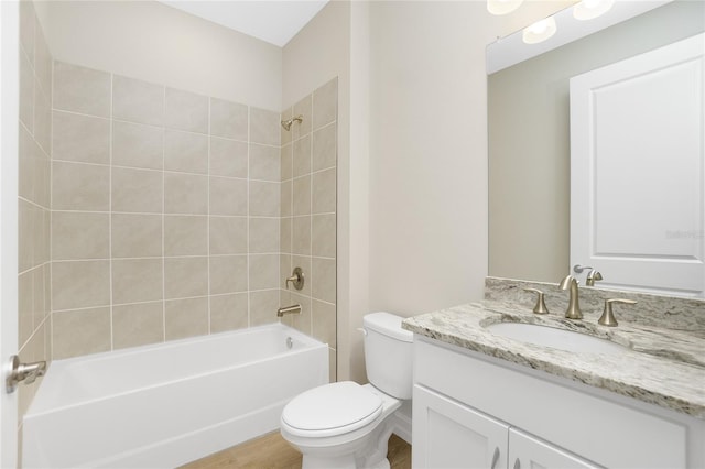 full bathroom featuring hardwood / wood-style floors, vanity, toilet, and tiled shower / bath combo