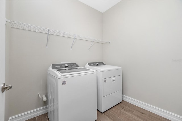 washroom with washing machine and dryer and light hardwood / wood-style floors