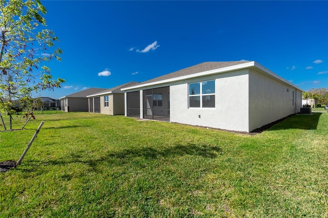 back of house with central air condition unit, a lawn, and a sunroom