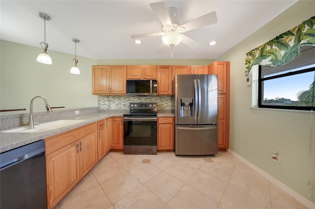 kitchen with sink, light stone counters, appliances with stainless steel finishes, backsplash, and decorative light fixtures