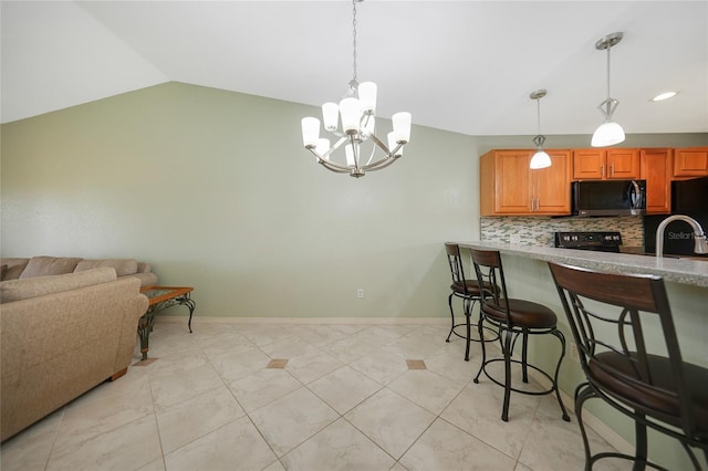 kitchen featuring a kitchen breakfast bar, decorative light fixtures, vaulted ceiling, a chandelier, and decorative backsplash