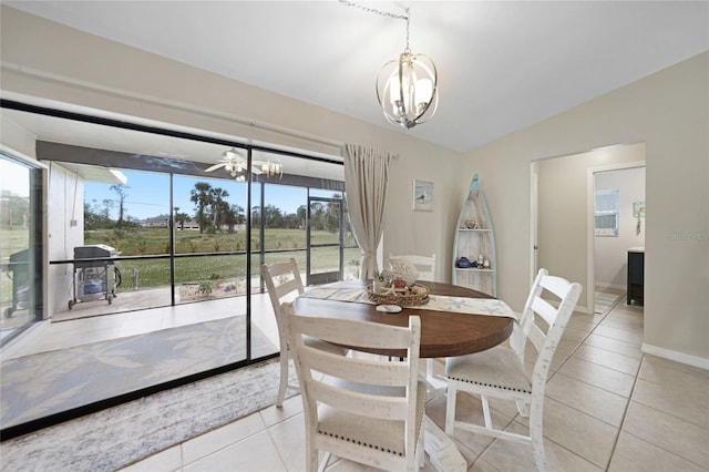 tiled dining room featuring vaulted ceiling, a healthy amount of sunlight, and ceiling fan with notable chandelier