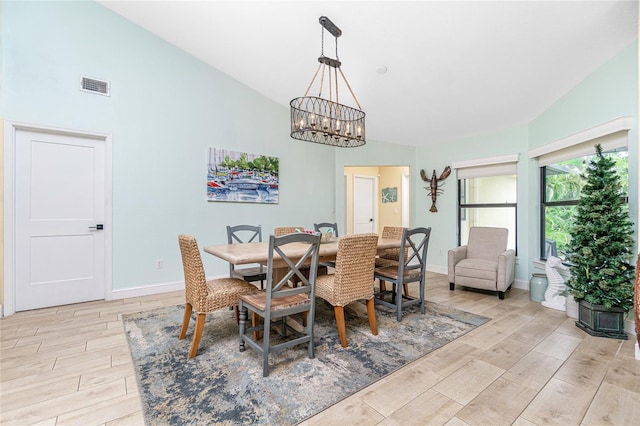 dining room featuring light hardwood / wood-style flooring, vaulted ceiling, and a notable chandelier