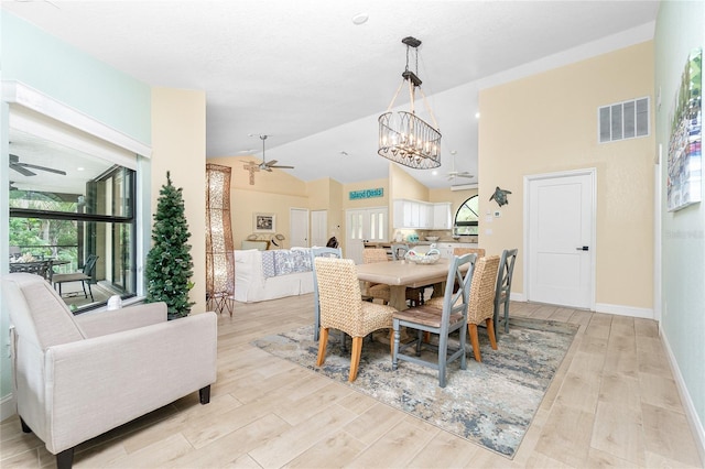 dining area featuring ceiling fan with notable chandelier, light hardwood / wood-style flooring, and high vaulted ceiling