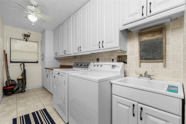 washroom with a textured ceiling, light tile patterned floors, cabinets, independent washer and dryer, and ceiling fan