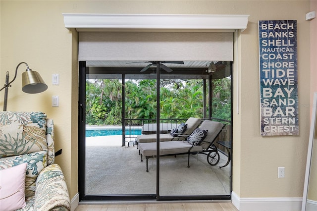 doorway with light wood-type flooring and ceiling fan