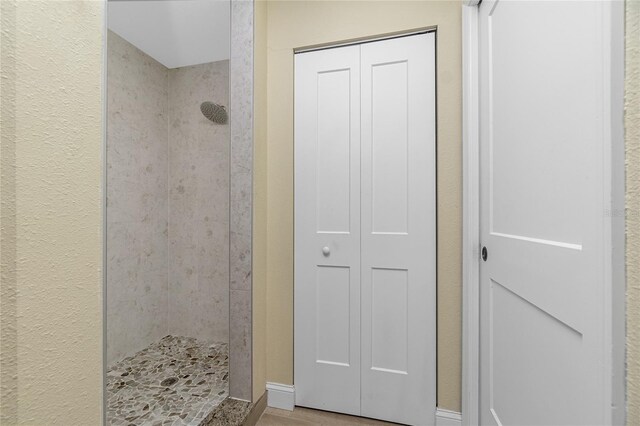 bathroom with wood-type flooring and tiled shower