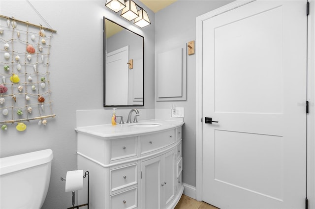 bathroom with wood-type flooring, vanity, and toilet