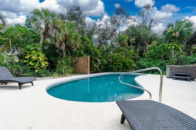 view of swimming pool featuring a hot tub and a patio