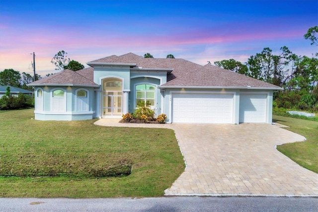 12194 Everglades Ave, Port Charlotte, FL 33981 - view of front of home featuring an attached garage, driveway, french doors, stucco siding, and a front yard