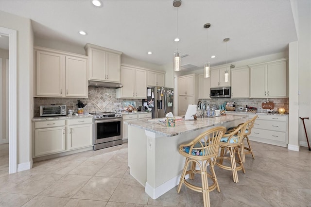 kitchen featuring tasteful backsplash, pendant lighting, a kitchen island with sink, and stainless steel appliances