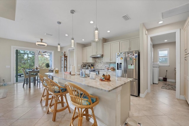 kitchen featuring a wealth of natural light, a kitchen island with sink, pendant lighting, and appliances with stainless steel finishes