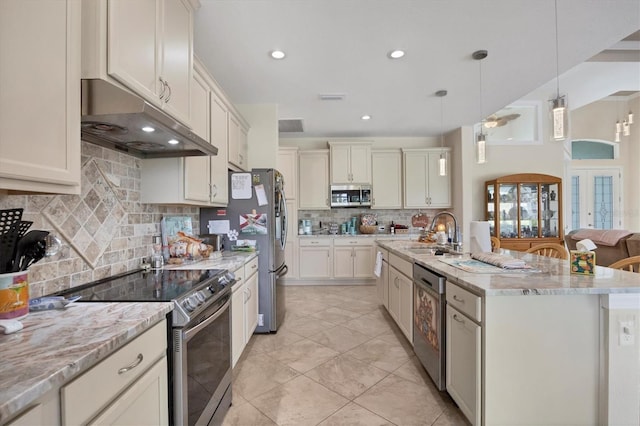 kitchen featuring a center island with sink, appliances with stainless steel finishes, hanging light fixtures, decorative backsplash, and sink