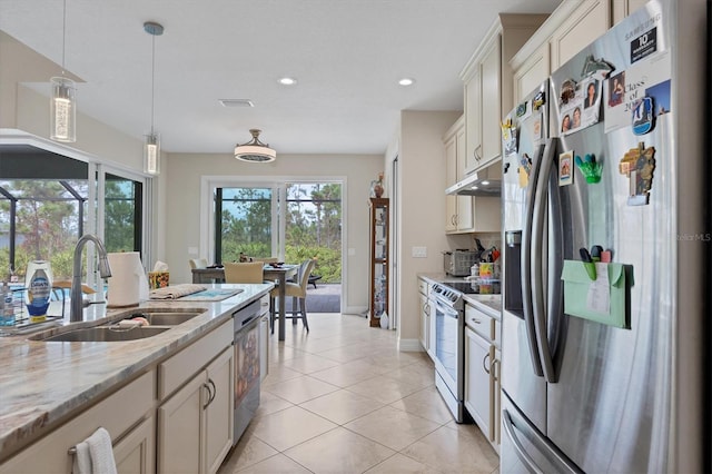 kitchen with stainless steel appliances, light tile patterned flooring, sink, light stone counters, and hanging light fixtures