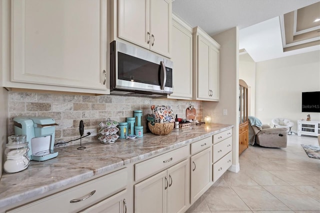 kitchen featuring decorative backsplash, light tile patterned floors, and light stone counters