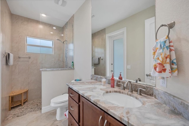 bathroom featuring toilet, vanity, and tiled shower