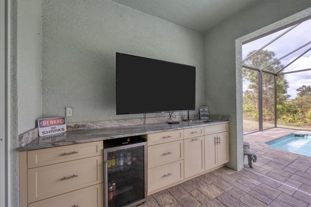 kitchen with white cabinetry, light stone countertops, and wine cooler