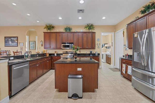 kitchen featuring stainless steel appliances, a kitchen island, light tile patterned floors, sink, and kitchen peninsula