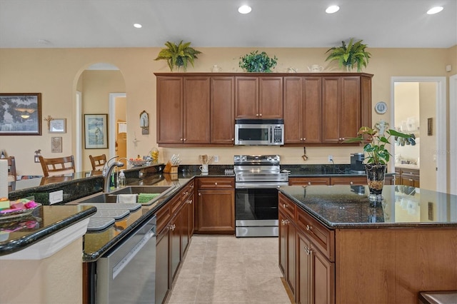 kitchen with dark stone counters, kitchen peninsula, sink, and stainless steel appliances