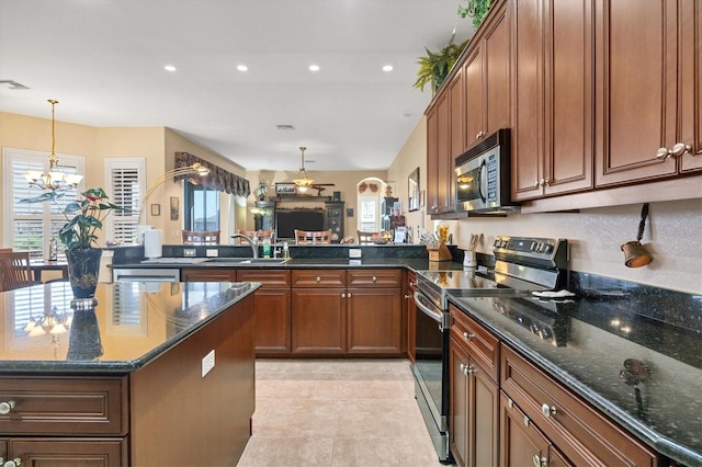 kitchen featuring sink, a chandelier, light tile patterned floors, appliances with stainless steel finishes, and dark stone countertops