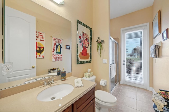 bathroom featuring tile patterned flooring, vanity, toilet, and a shower with door