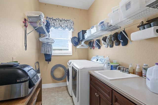 laundry area featuring light tile patterned floors, separate washer and dryer, sink, and cabinets