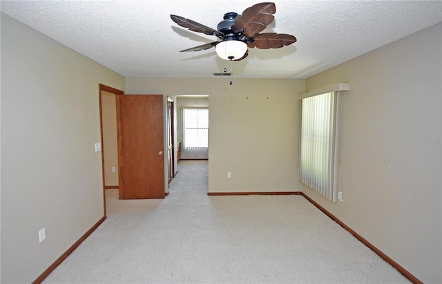 spare room featuring ceiling fan, a textured ceiling, and light carpet