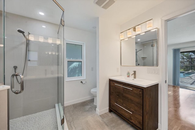 bathroom with vanity, a shower with door, and toilet