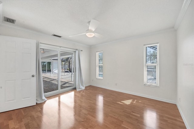 spare room featuring wood-type flooring, ornamental molding, a textured ceiling, and ceiling fan