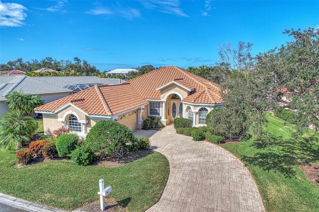 mediterranean / spanish-style home featuring a garage and a front yard