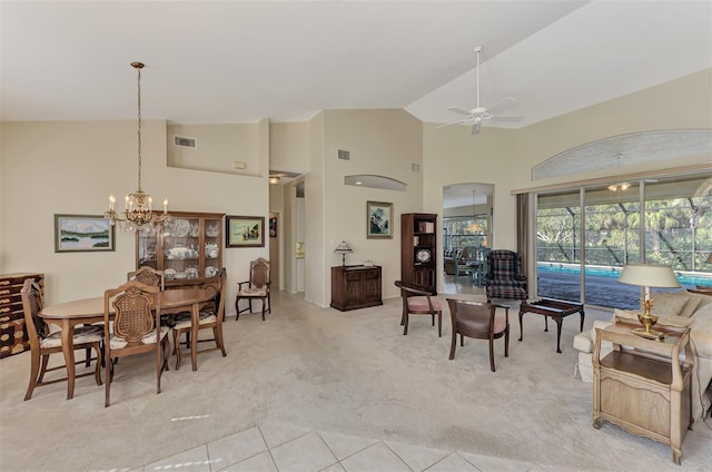 dining room featuring ceiling fan with notable chandelier, light carpet, and high vaulted ceiling