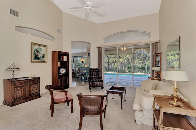 sitting room with light carpet, ceiling fan, a high ceiling, and a pool