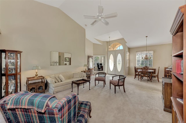 living room with ceiling fan with notable chandelier, light colored carpet, and high vaulted ceiling