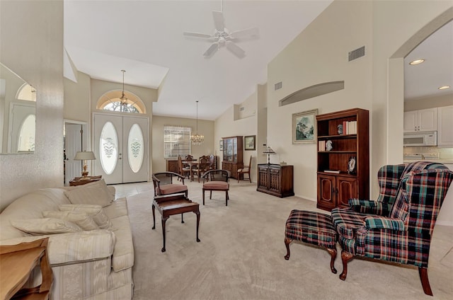 carpeted living room featuring high vaulted ceiling, french doors, and ceiling fan with notable chandelier