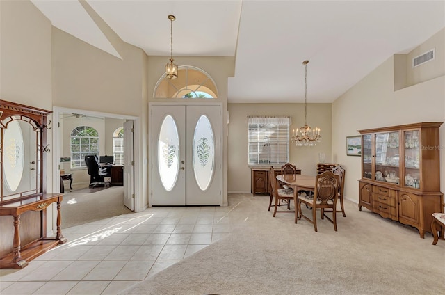 carpeted entryway with french doors, ceiling fan with notable chandelier, and a towering ceiling