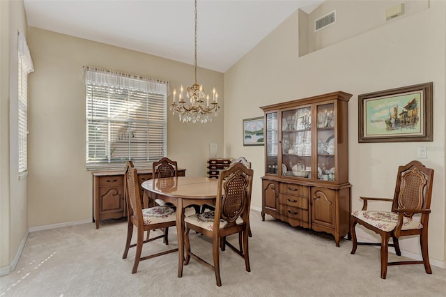 dining area with light colored carpet, an inviting chandelier, and high vaulted ceiling