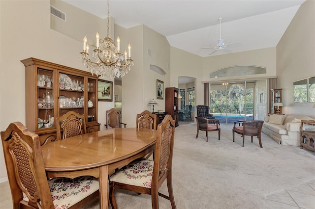 carpeted dining room with high vaulted ceiling and ceiling fan with notable chandelier