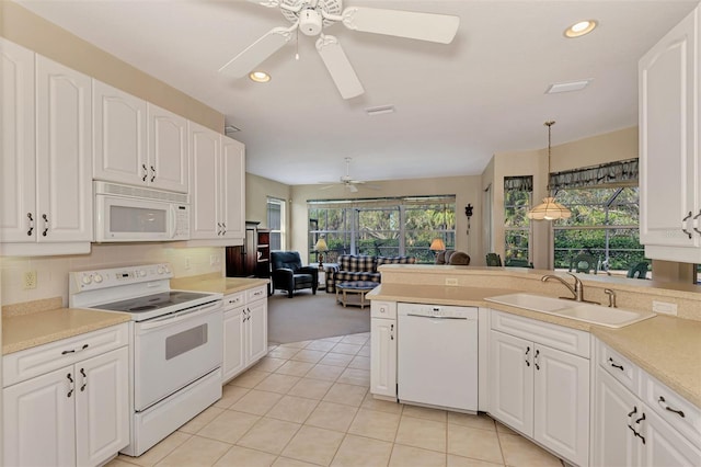 kitchen with light tile patterned flooring, sink, hanging light fixtures, white appliances, and white cabinets